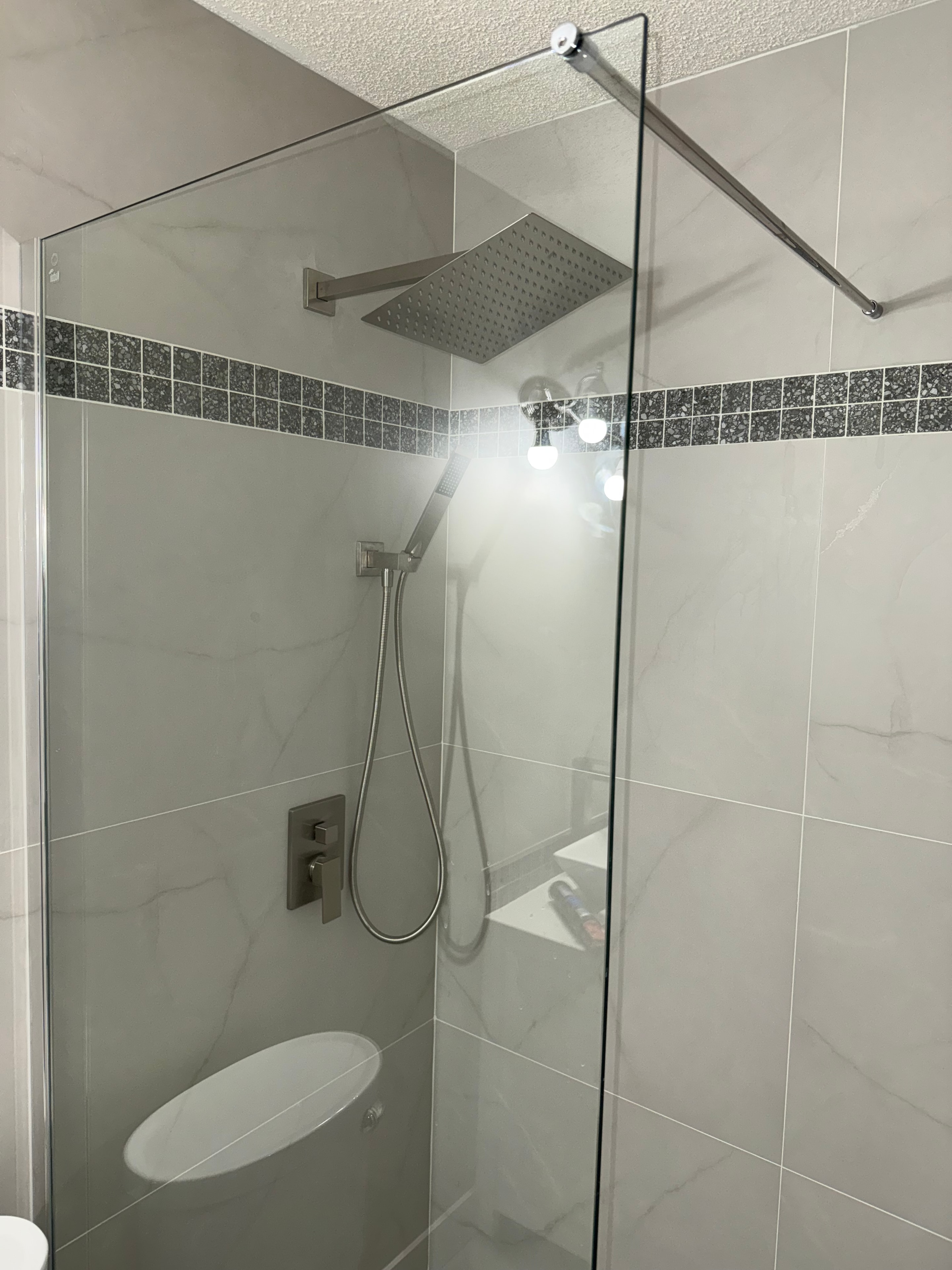 Walk-in shower with frameless glass, mosaic accent strip and rain head