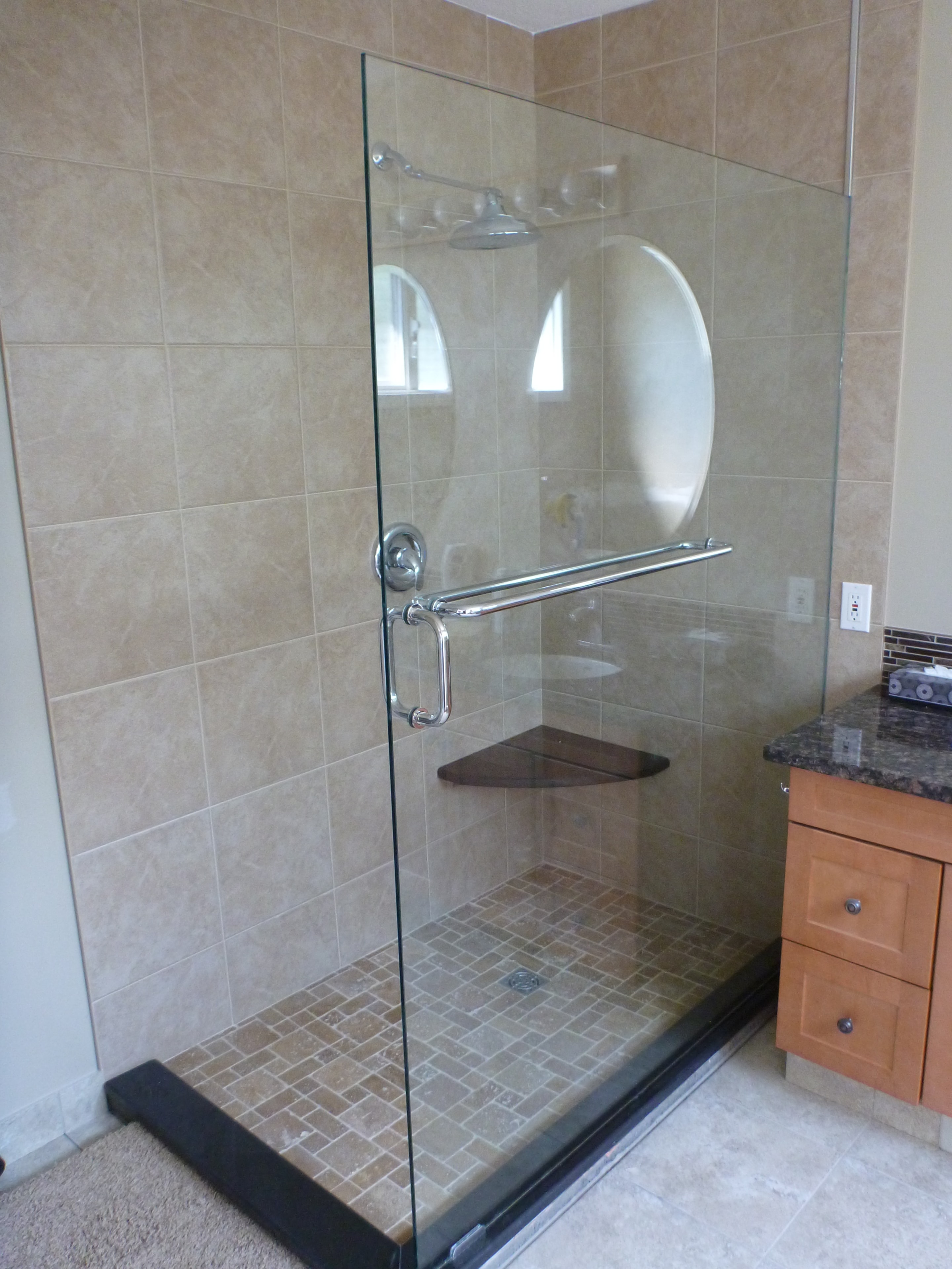 Tempered glass shower enclosure with custom tile floor and mosaic accents